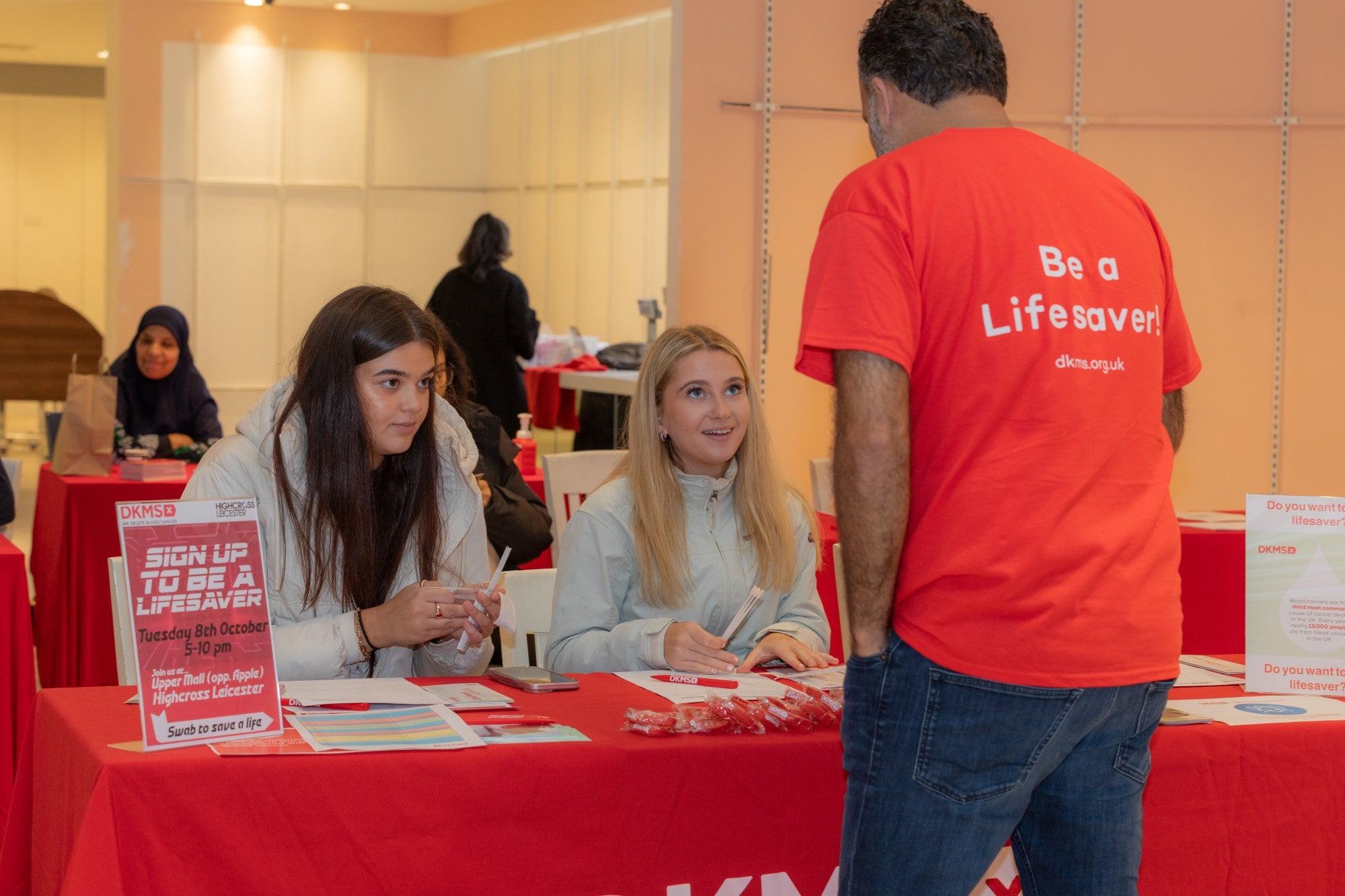 Three people at a DKMS stand