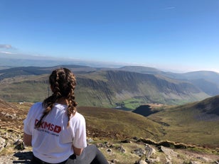 Woman sat in a DKMS t-shirt in the countryside
