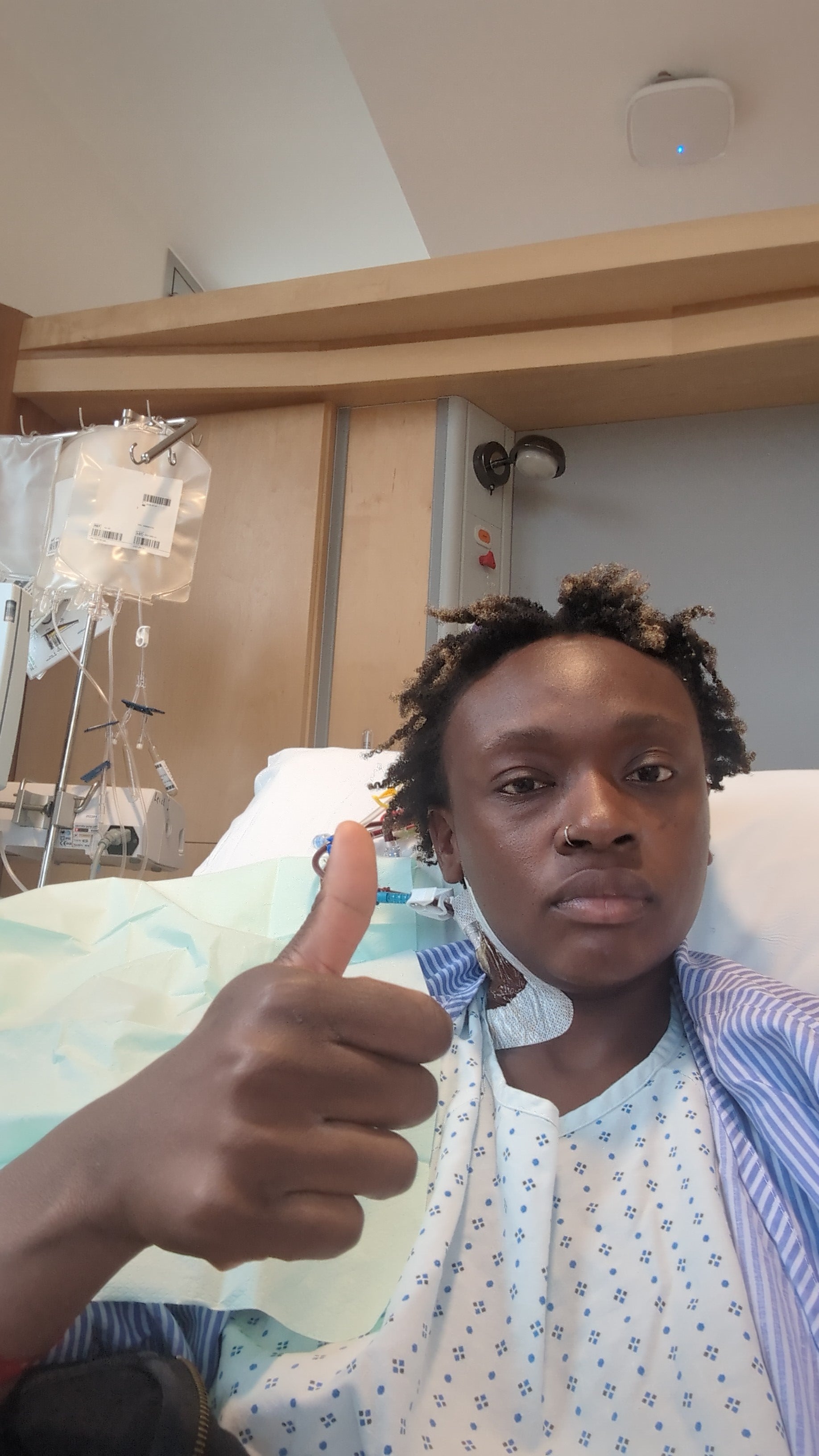 African woman giving a thumbs up in a hospital bed