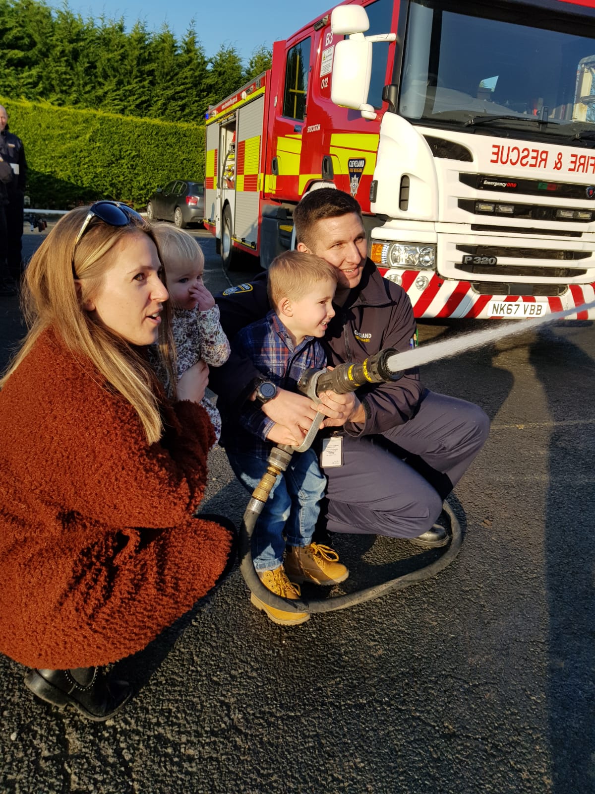 Firefighter and his family holding a hose