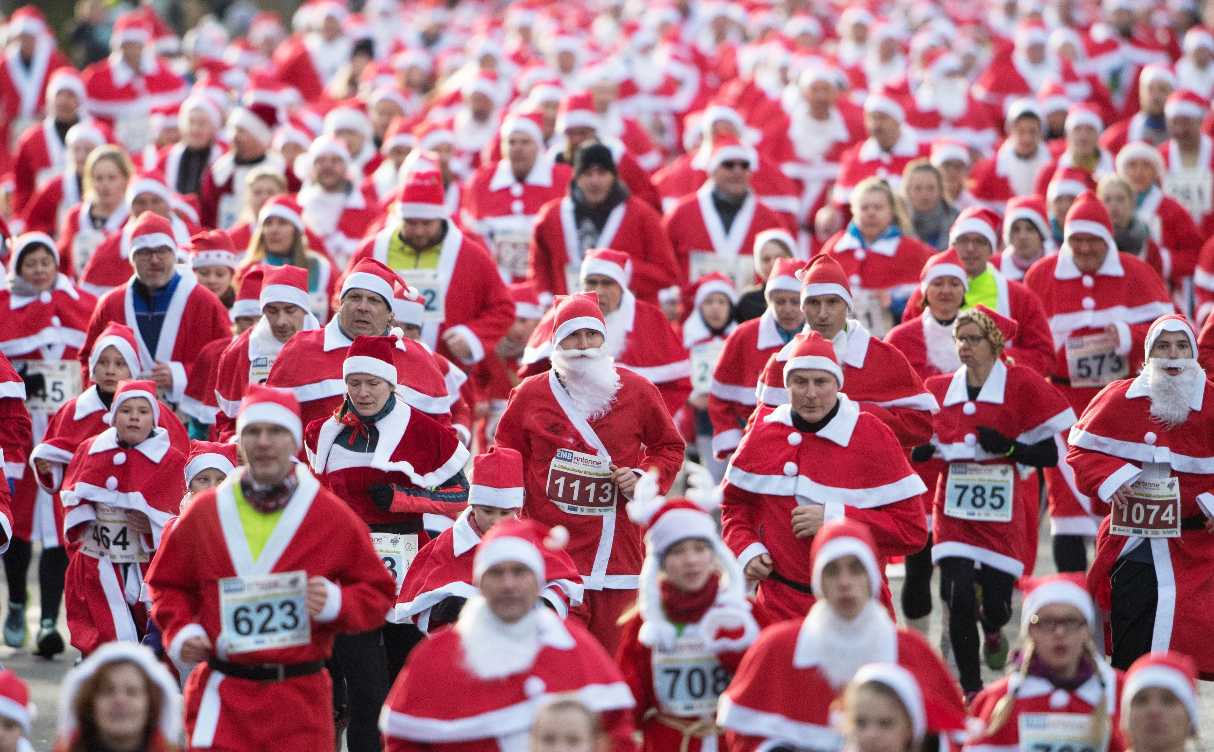 Lots of people dressed in santa suits running