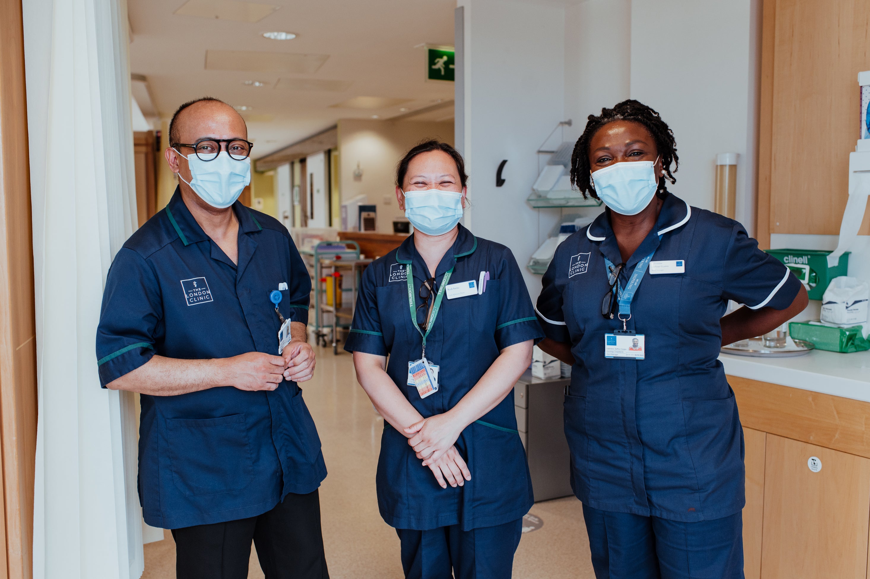 Three people dressed in medical tunics and masks in a hospital