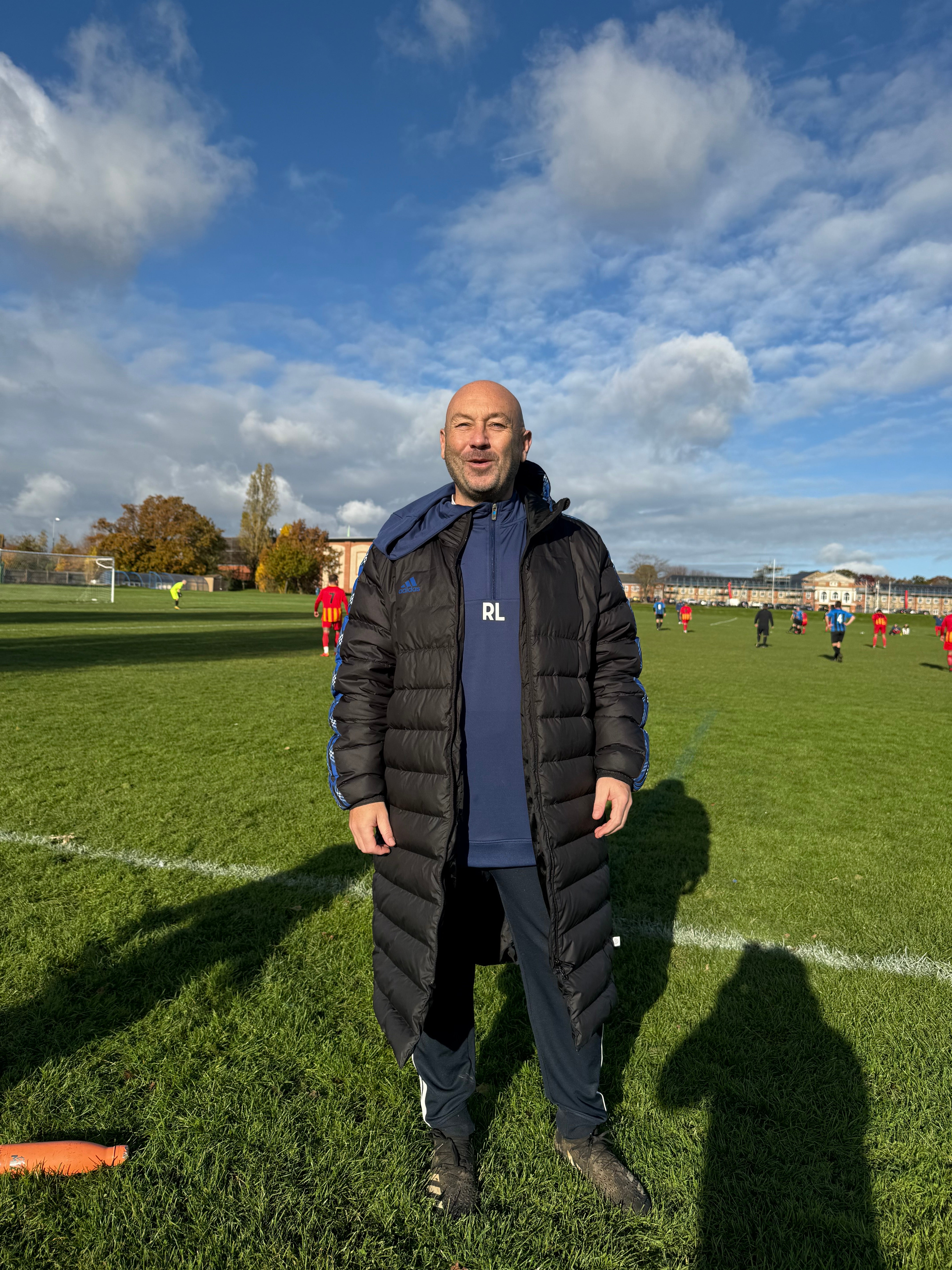 Elderly white man smiling on a football field 