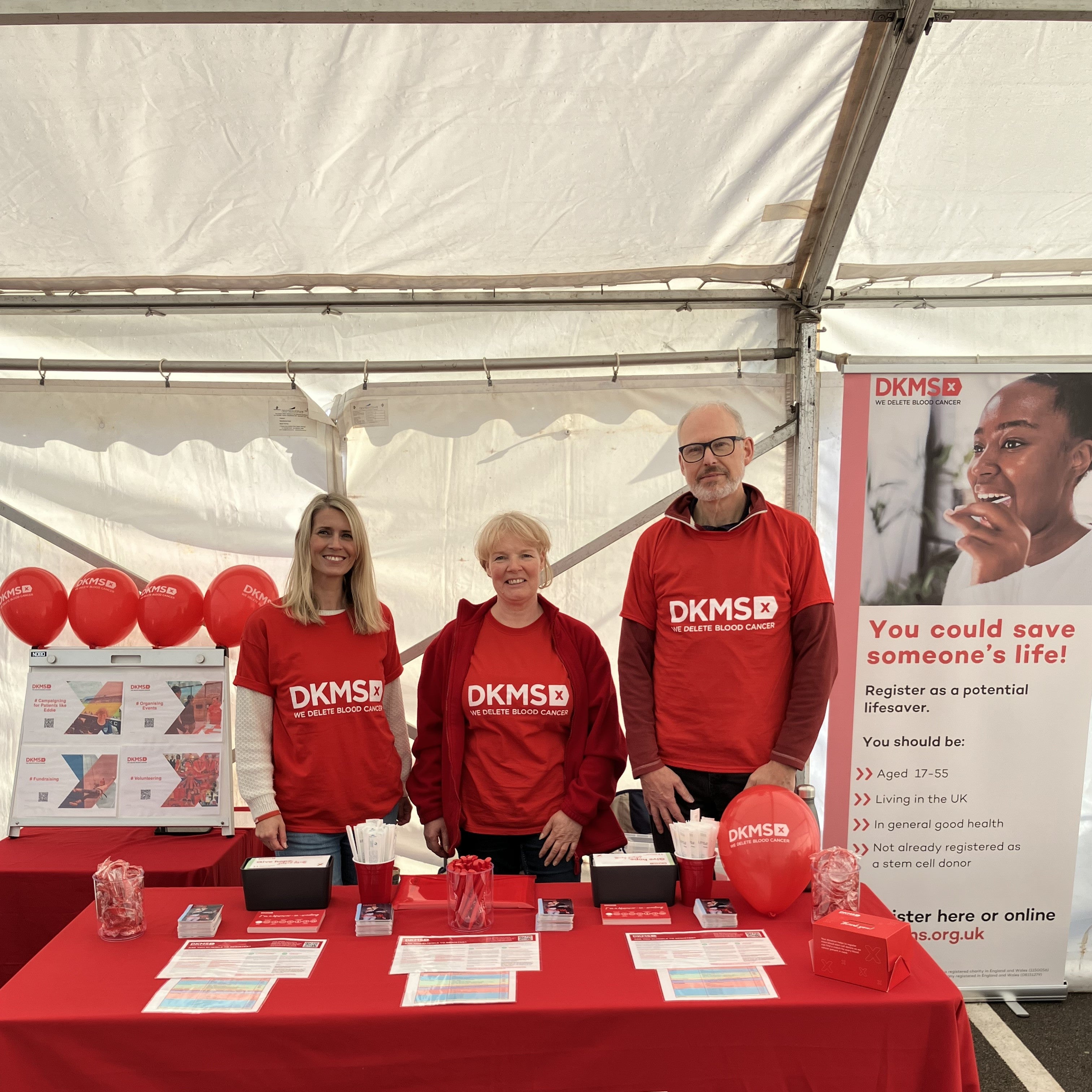 Three DKMS volunteers at an event registration stall