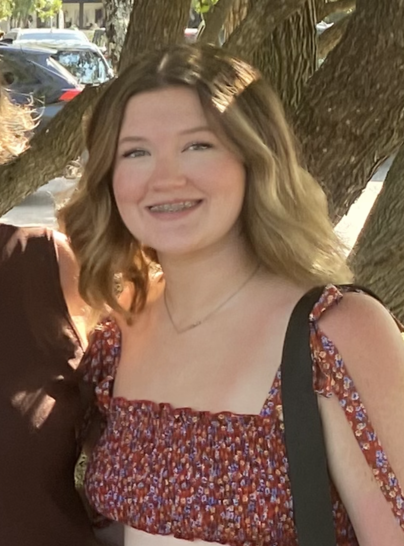 Payton in a summer dress standing under a tree