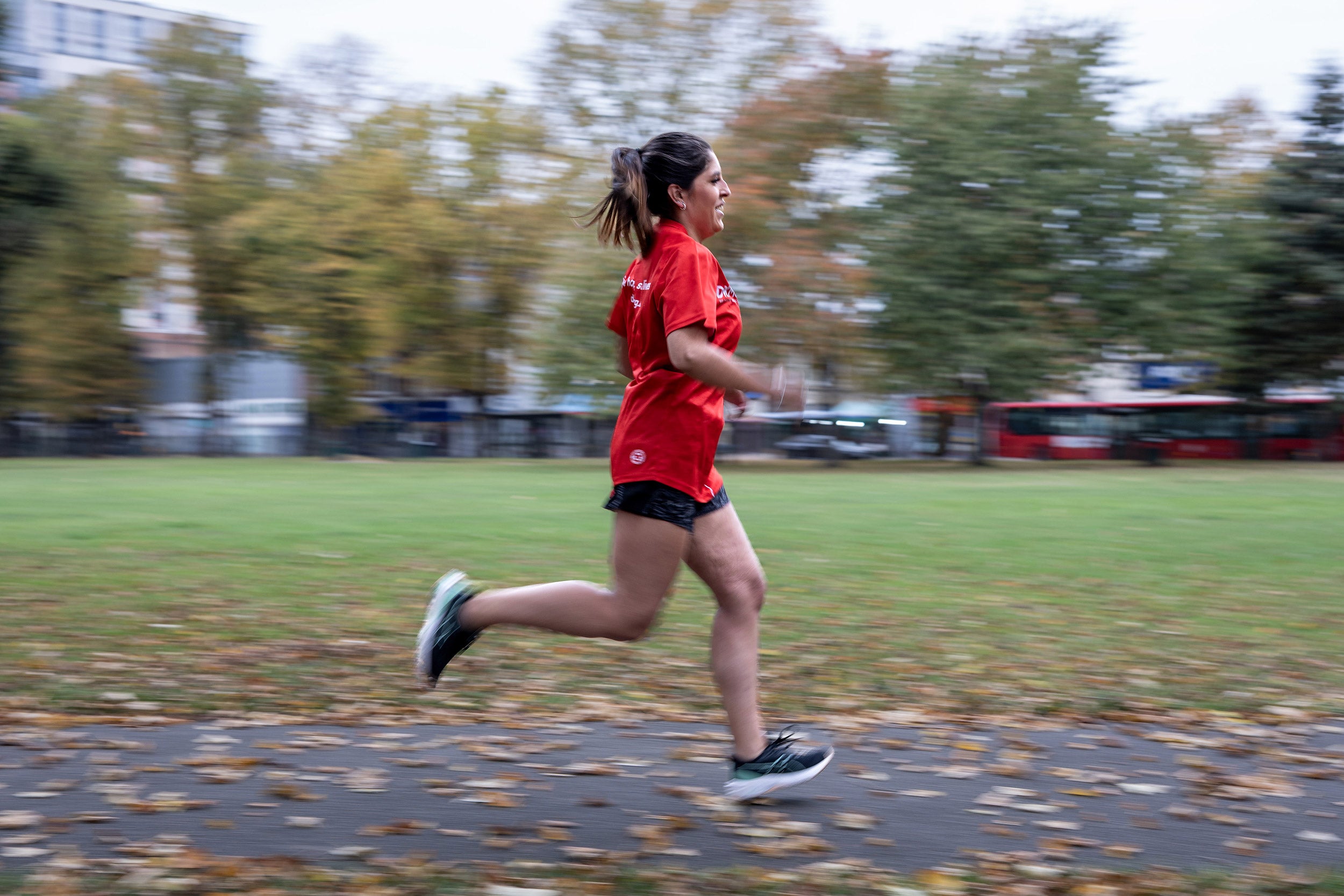 Woman in red top running through a park