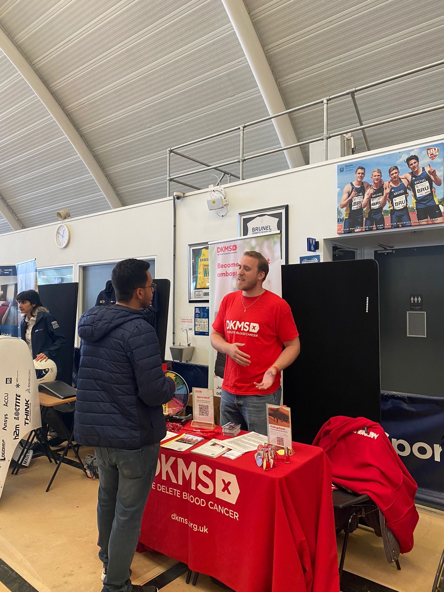 Middle aged white man speaking to young man at an event table
