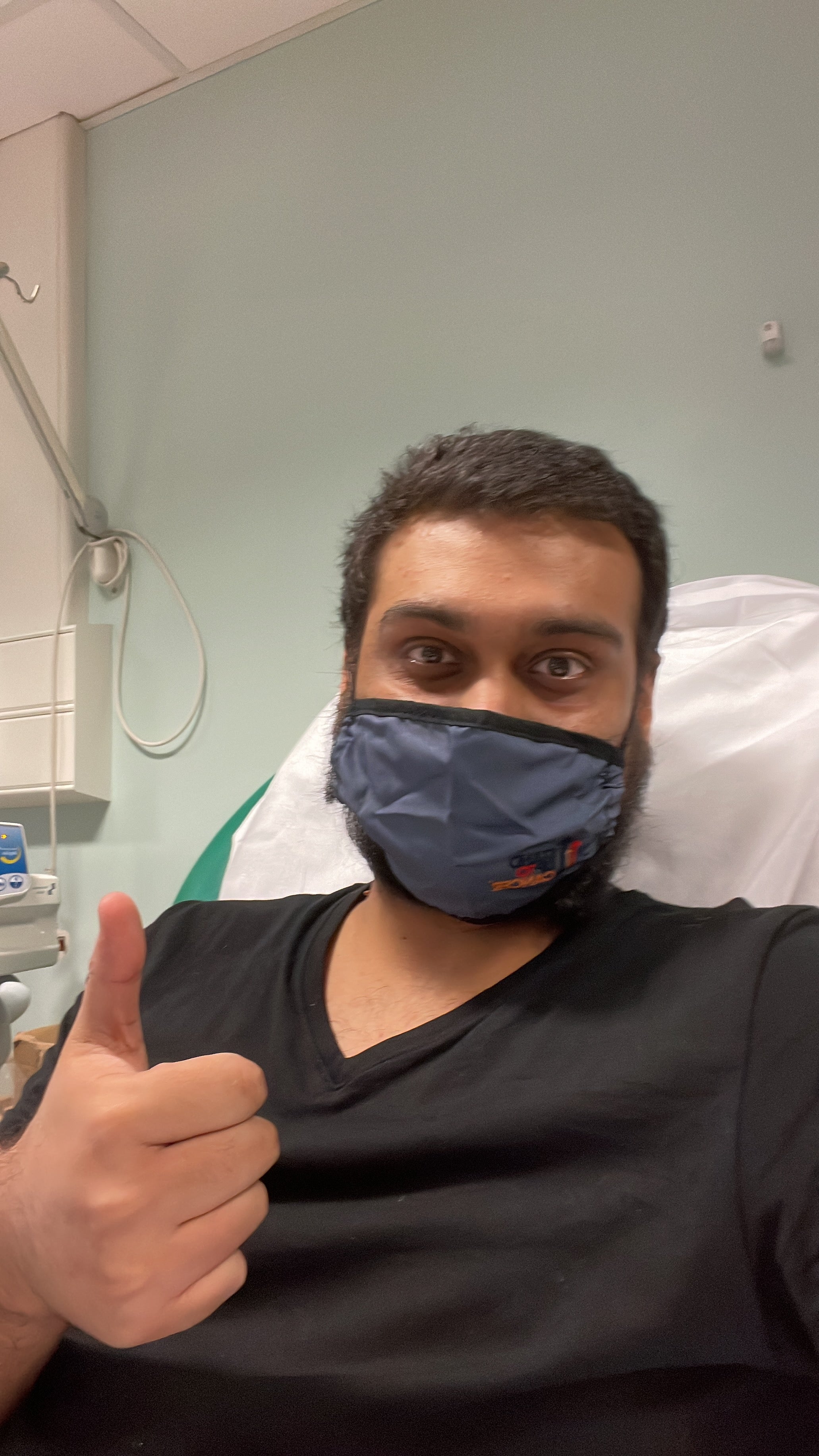 Fahad wears a mask with his thumbs up.
