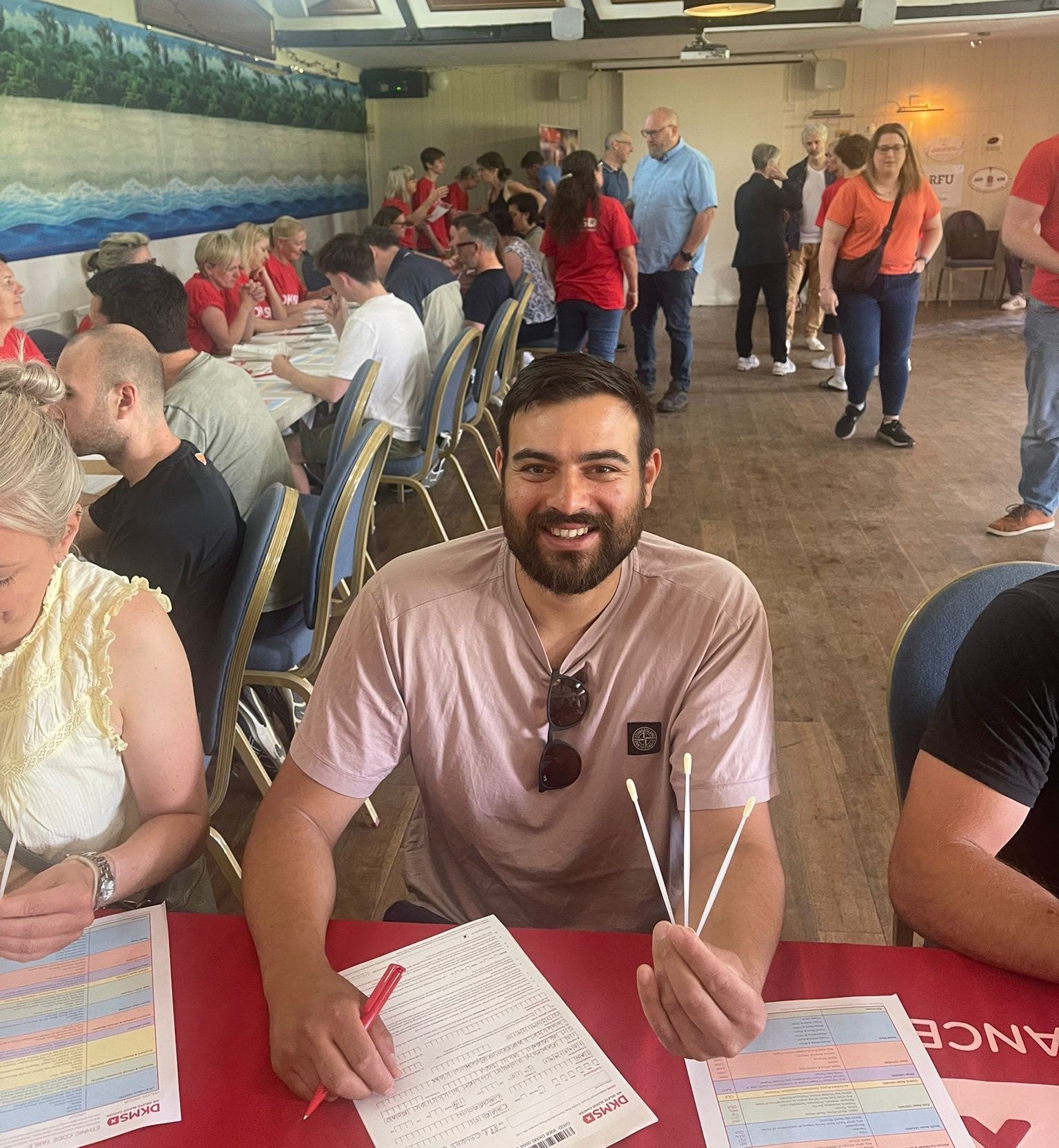 Man smiling and holding swabs at a donor registration event