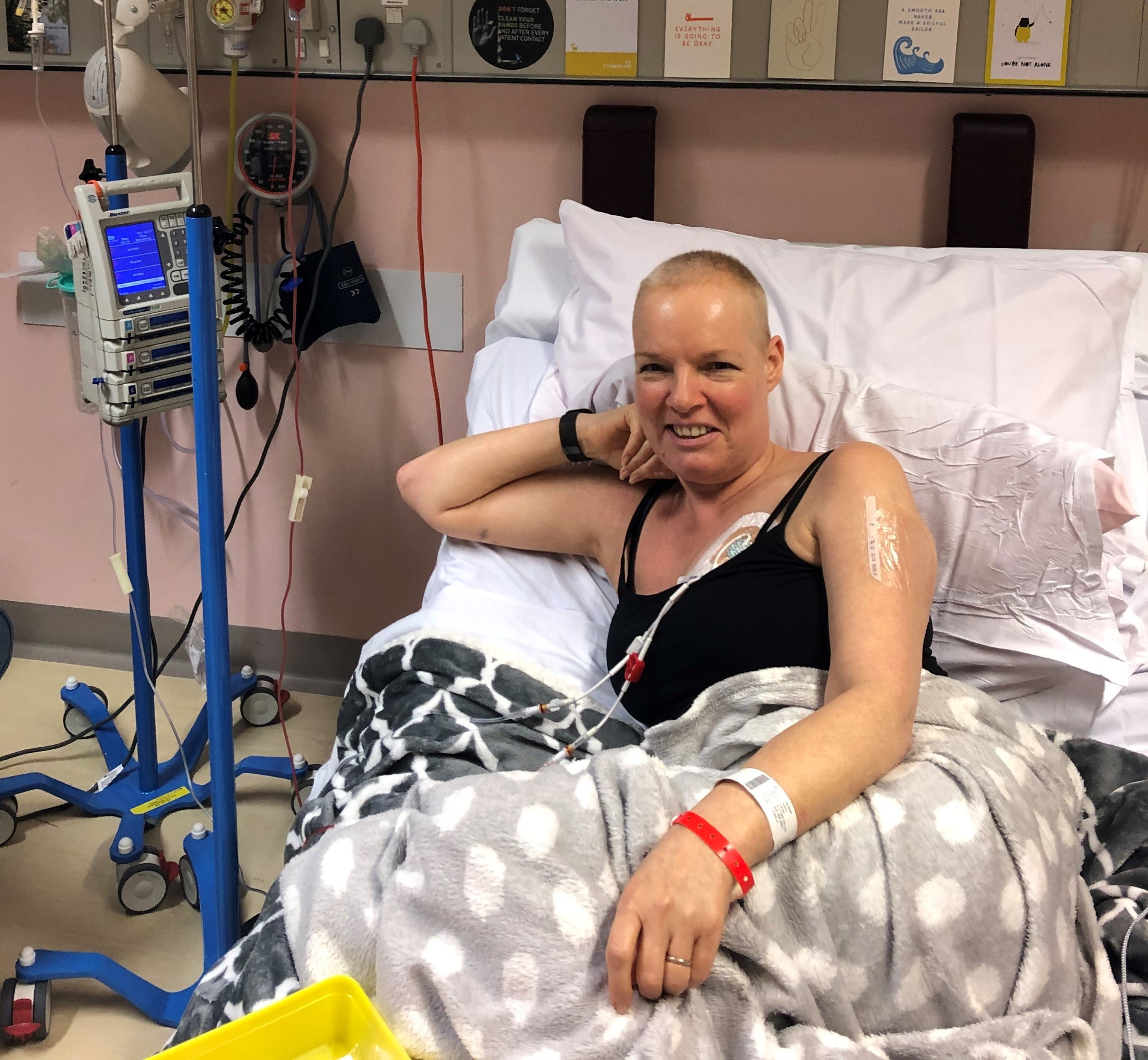 Elderly white woman lying in hospital bed and smiling connected to tubes 