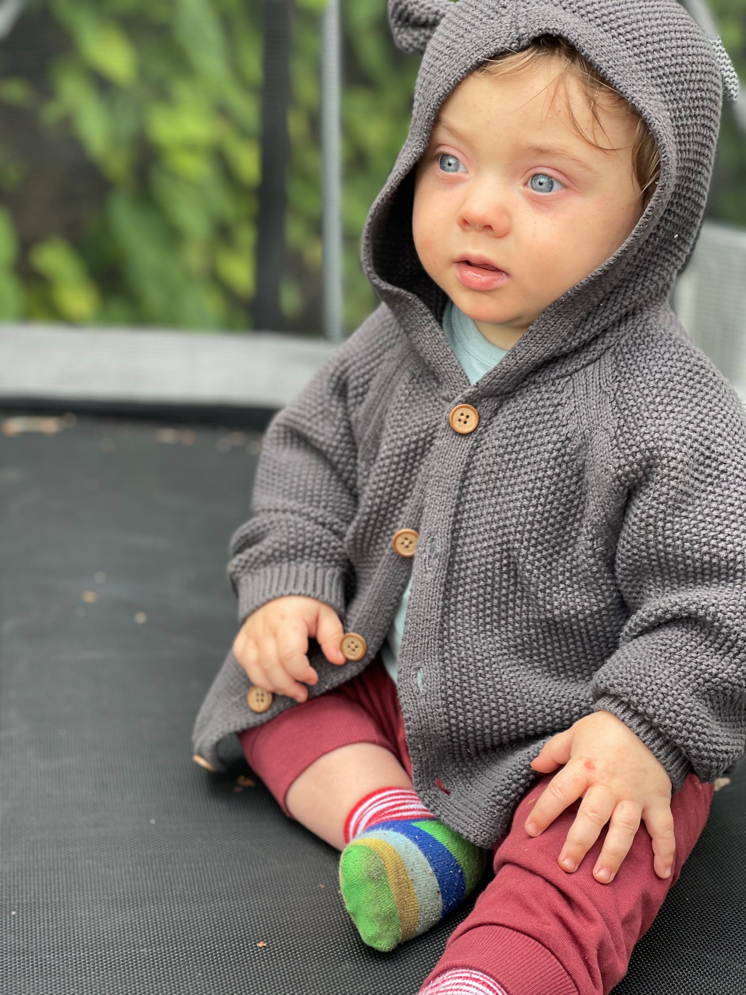 Gustavs wearing a grey knitted hooded jacket