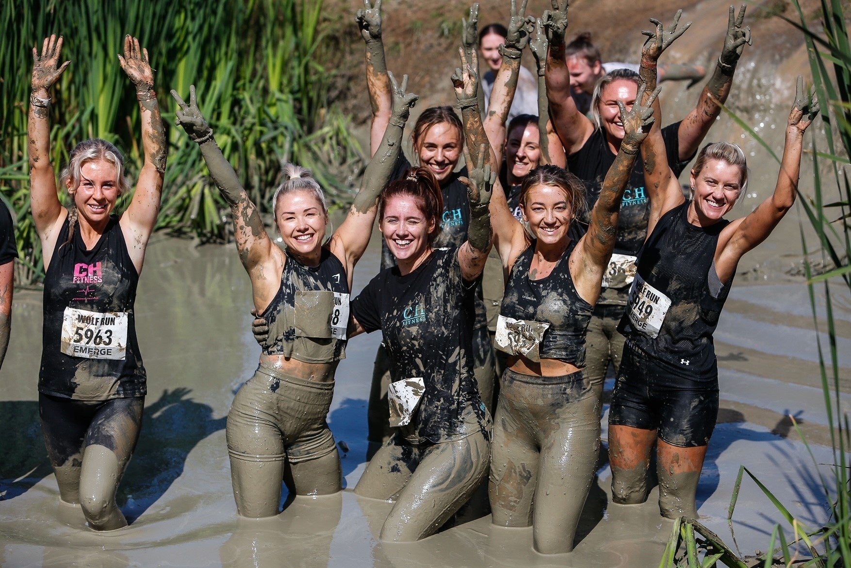 Group of women covered in mud on obstacle course