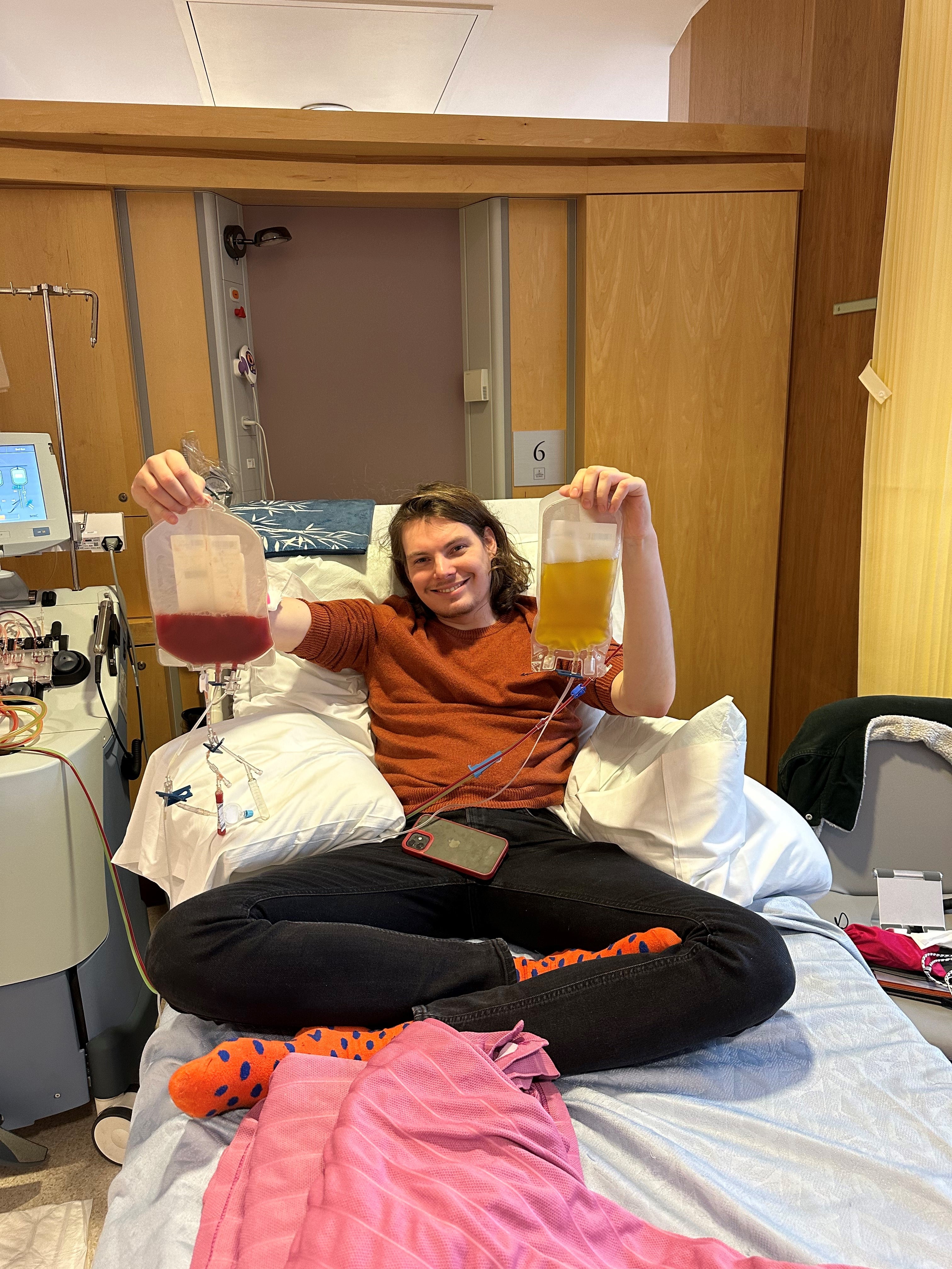 Young man smiling on a hospital bed and holding bags of stem cells