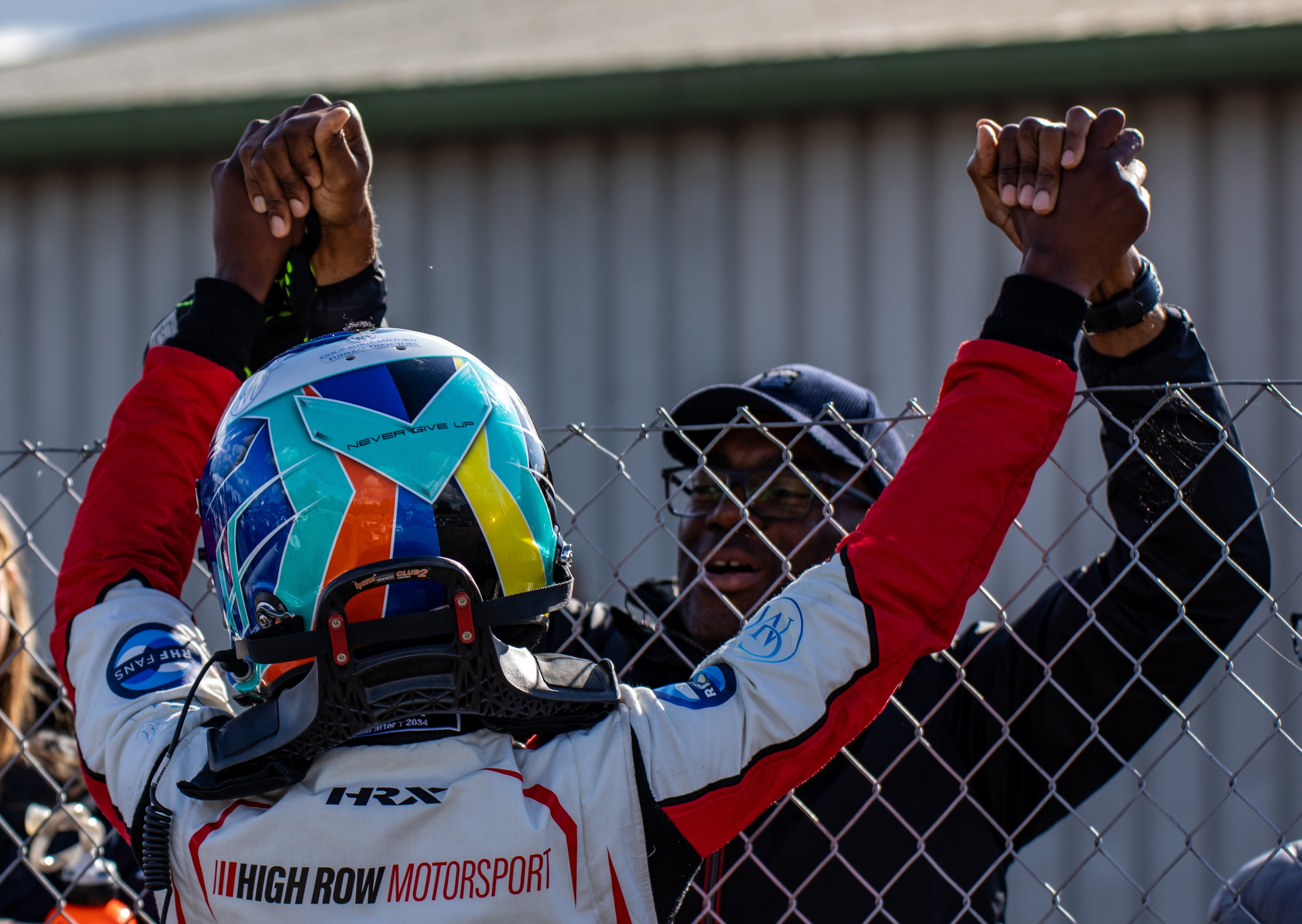 Cecil from Rochdale and his son embracing and holding hands over the fence after a motocross race