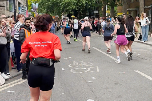 Girl wearing DKMS Running top runs in Half marathon, with other runners and supporters in the background