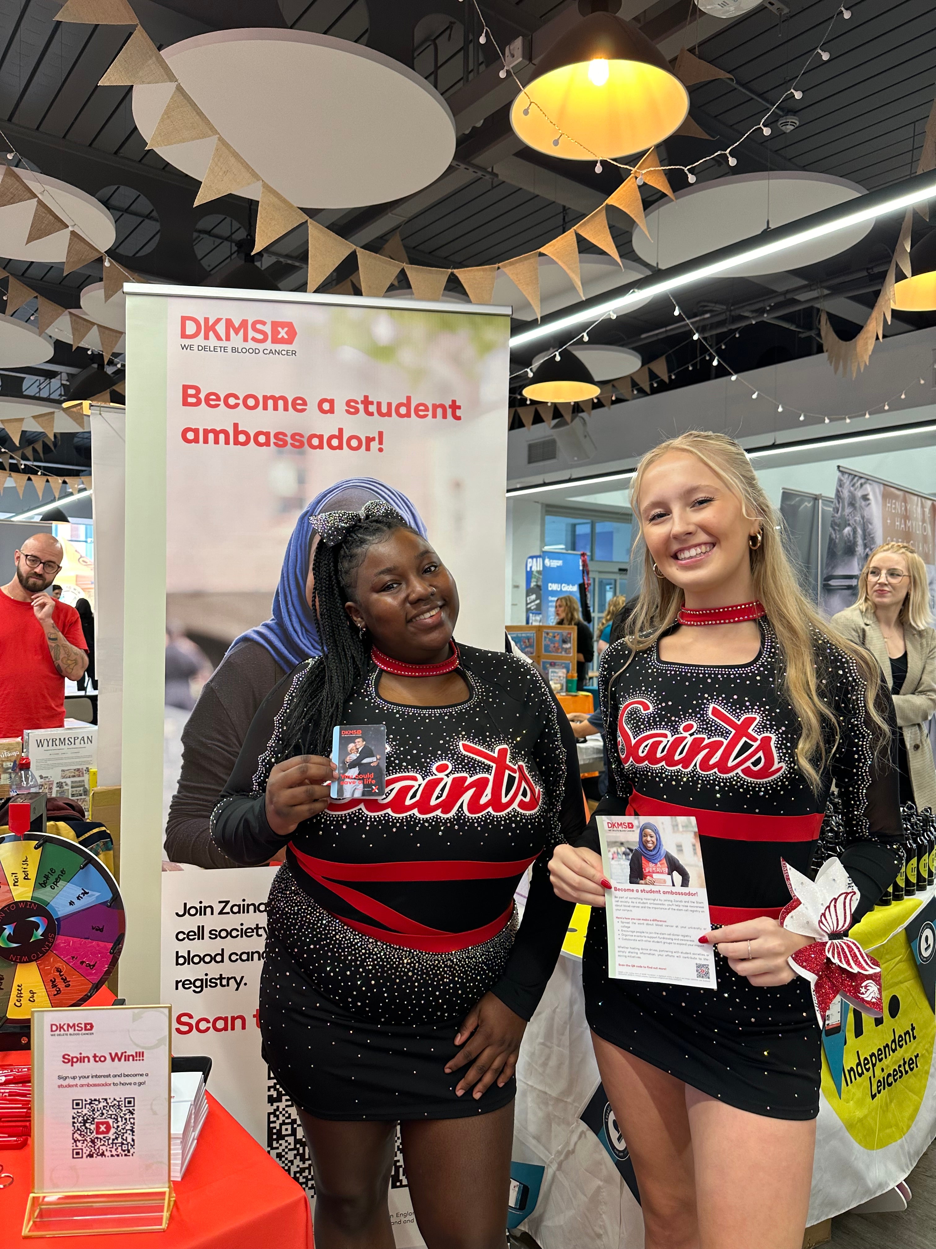 Two Cheerleaders at DeMontford University holding DKMS branded material