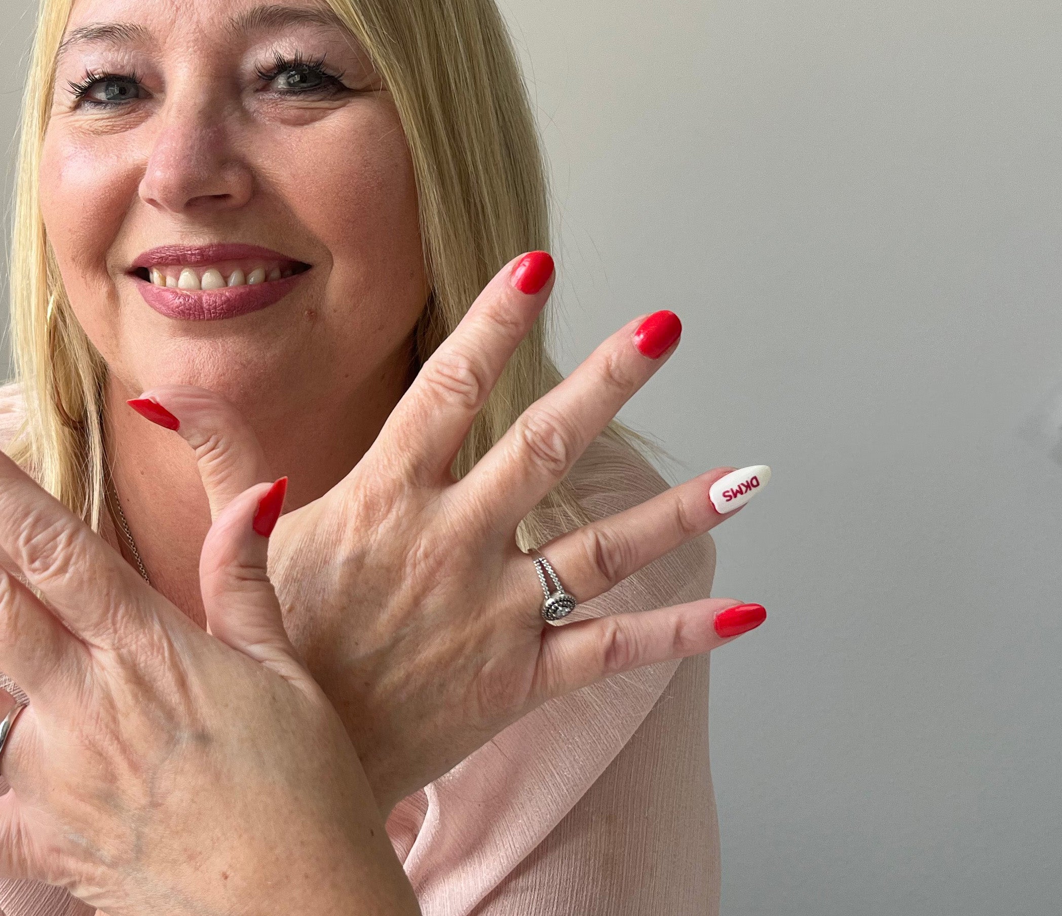 Caroline displaying her red polished and DKMS branded fingernails 