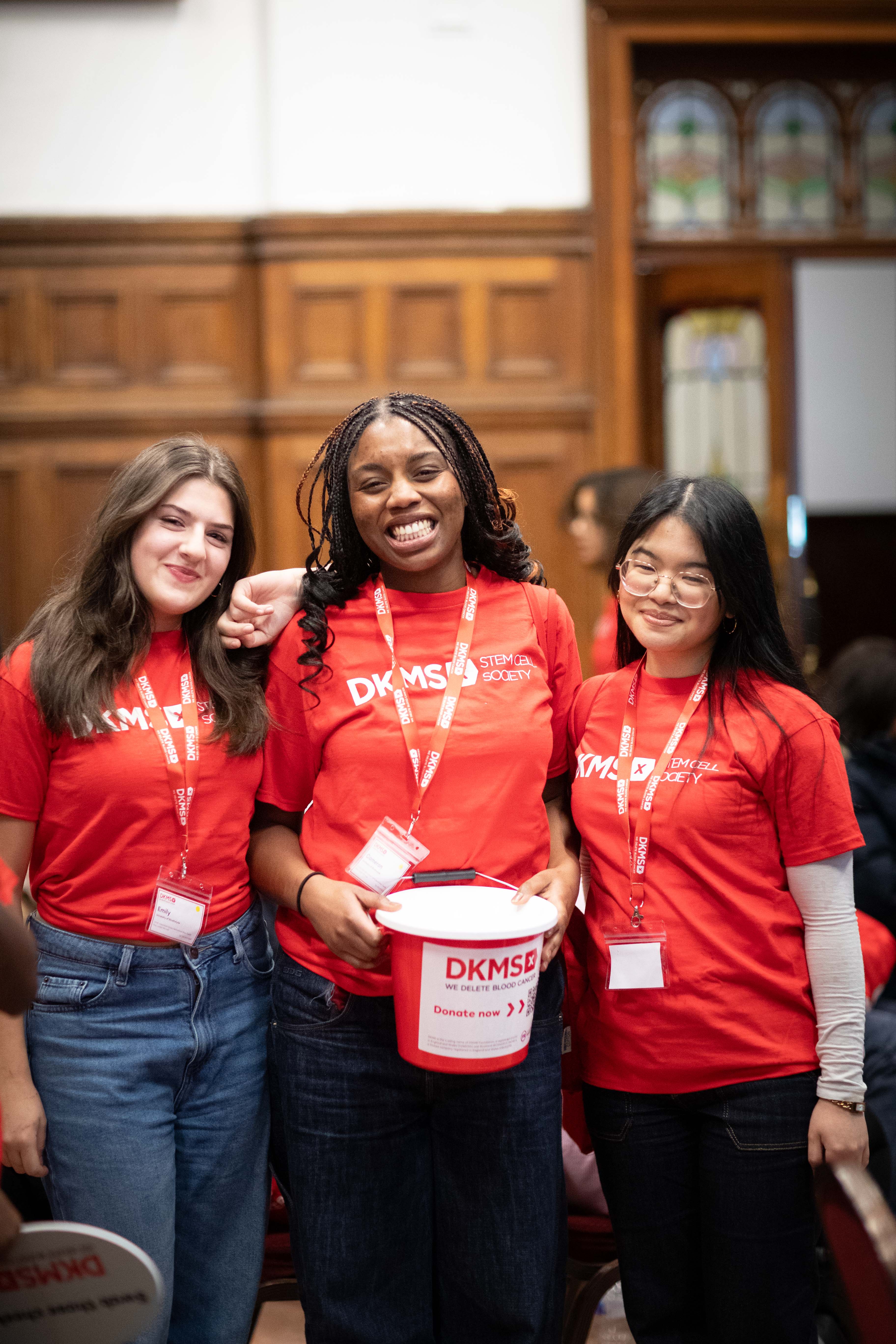 3 student ambassadors holding a DKMS collection bucket