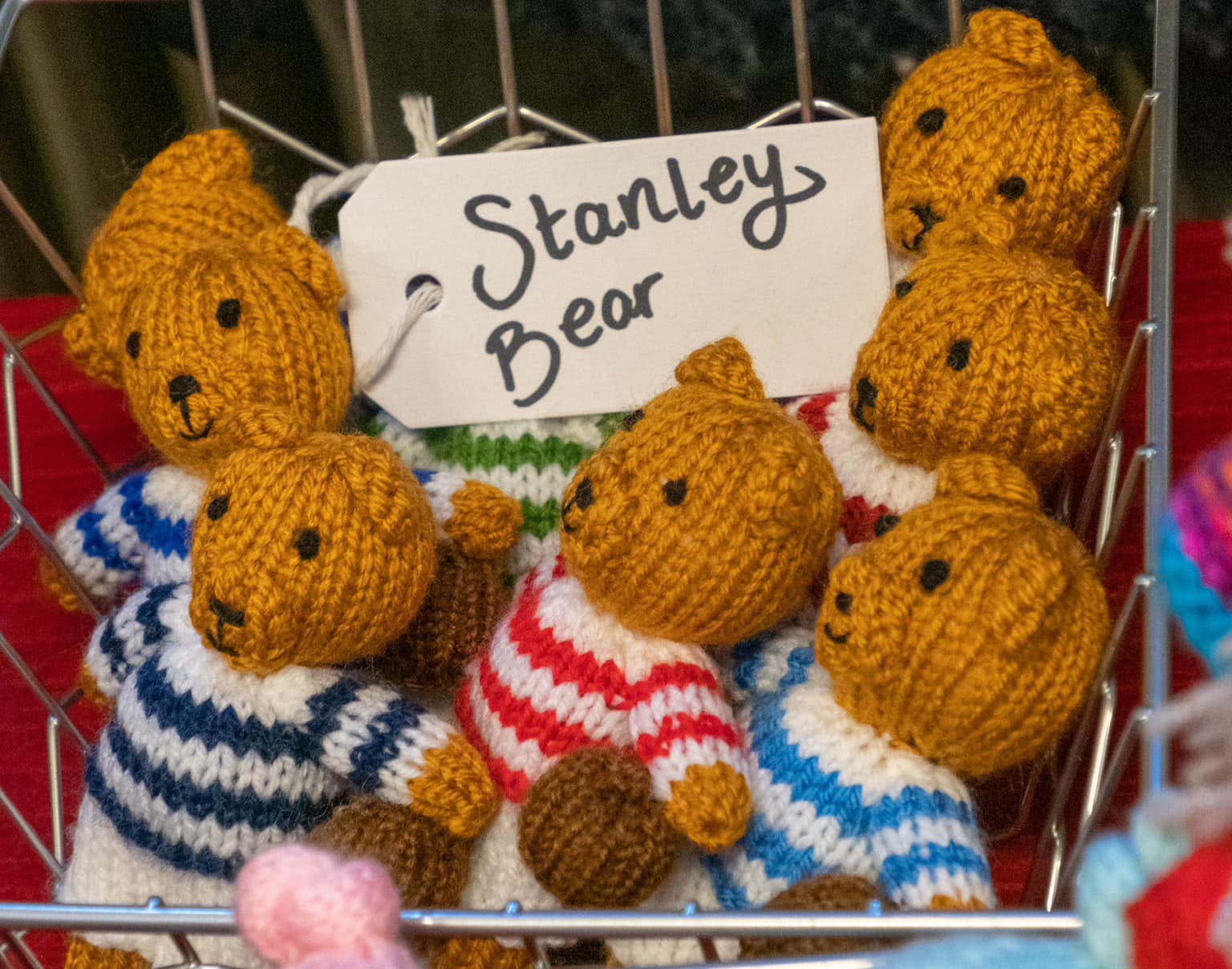 Basket of knitted teddy bears in stripy jumpers