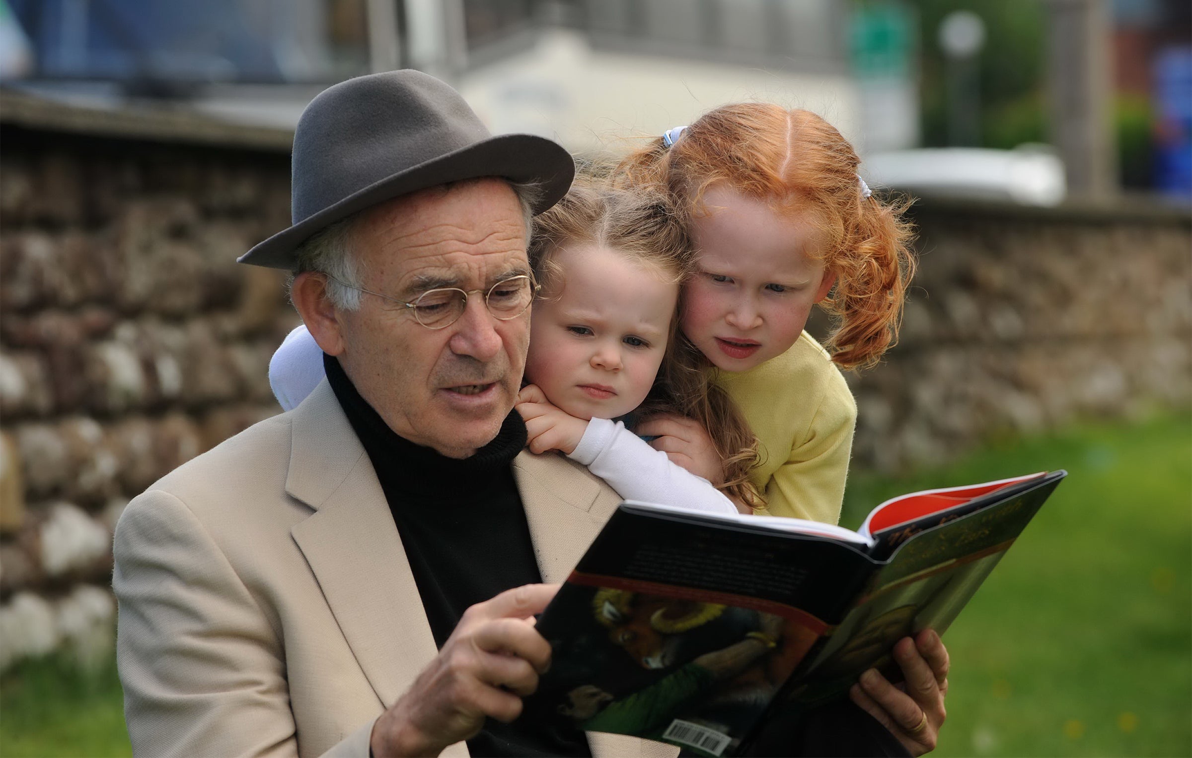 A man reading a book to two kids