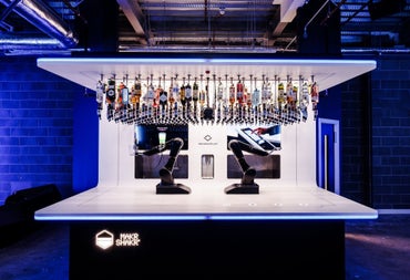 Two robotic arms under optics holding bottles of spirits