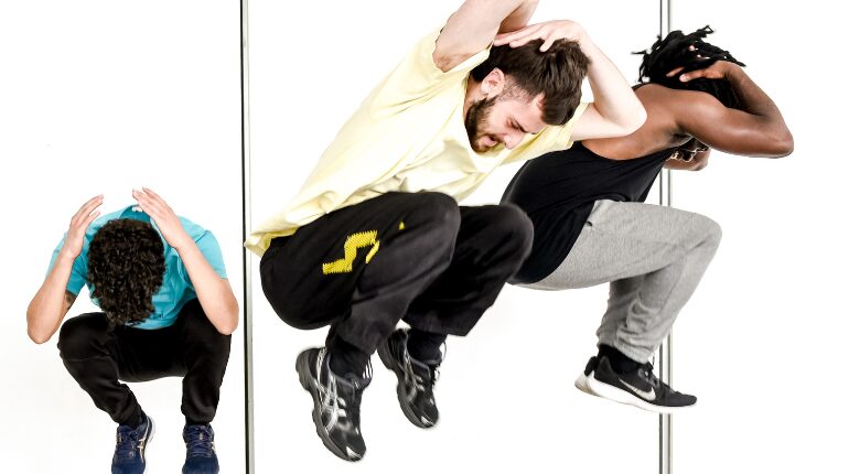 3 people in crouched position with arms covering their lowered heads.