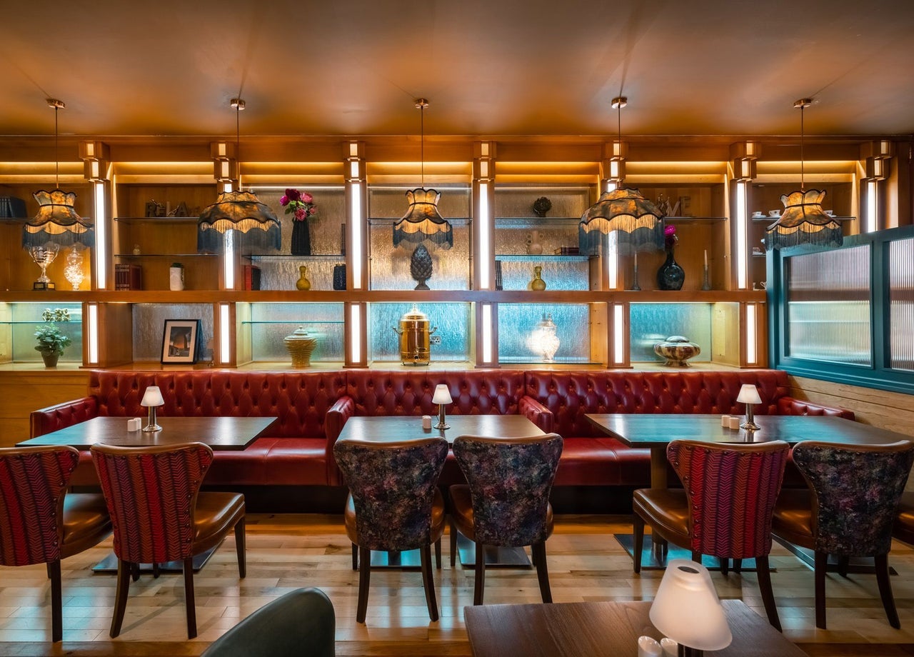 Dining tables and chairs in a restaurant with mirrors and lighting behind