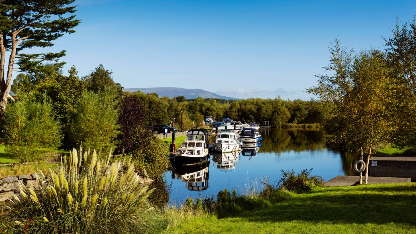 Cruisers moored at Leitrim Village in County Leitrim on a sunny day near some trees