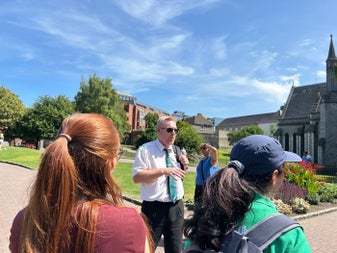Two people listening to a tour guide speak