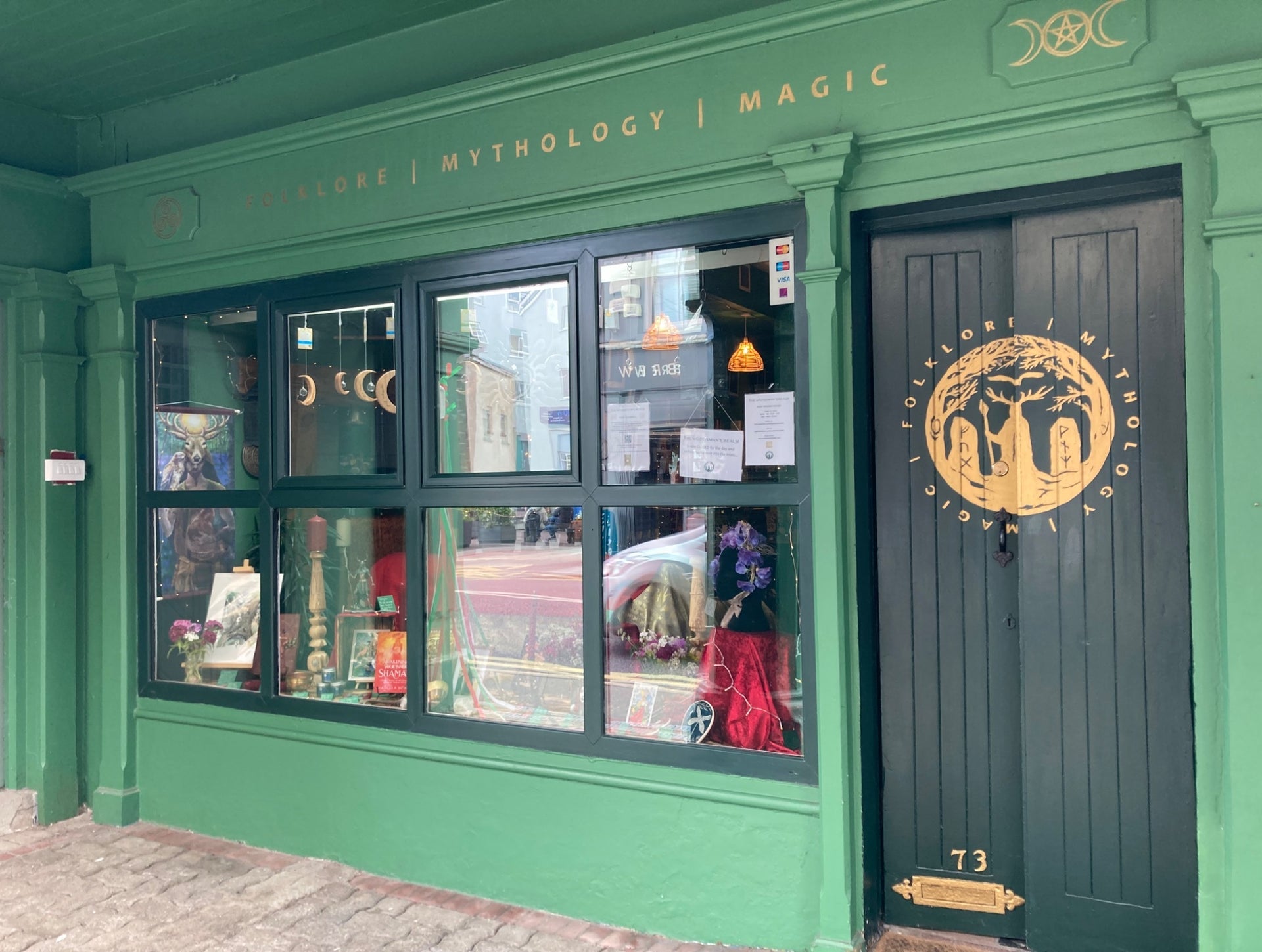 The exterior of a shop front painted green with gold lettering signage