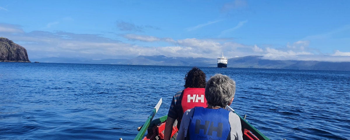 Two ladies in a rowing looking at a cruise ship in the bay