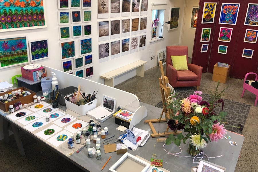 Desk with artist supplies and works in progress in an artist's studio