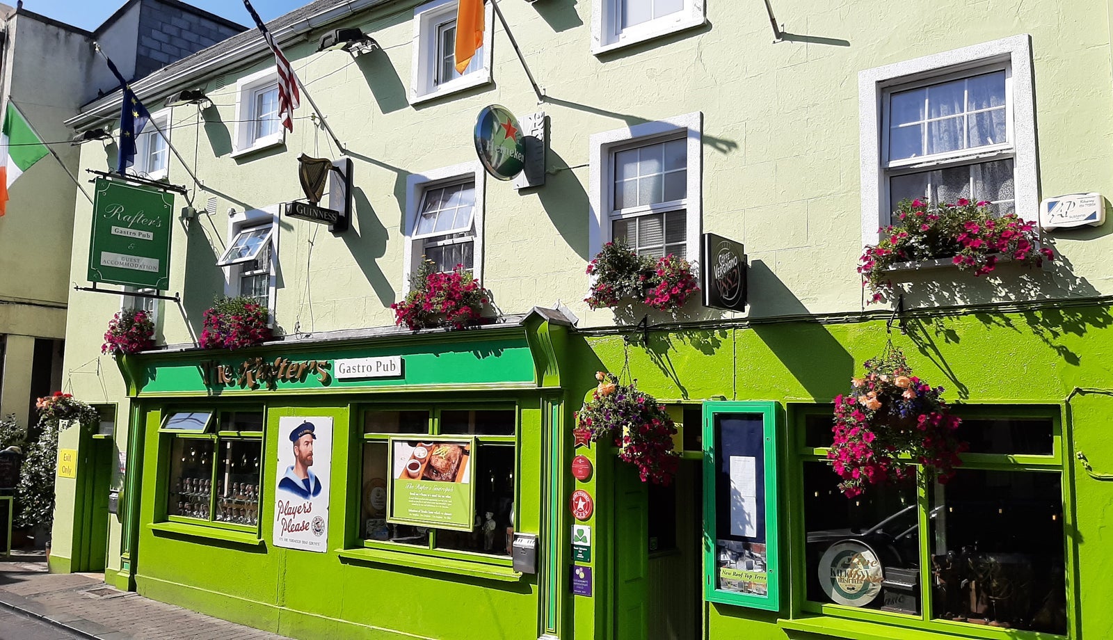 A brightly coloured pub exterior with floral baskets along the walls and windows