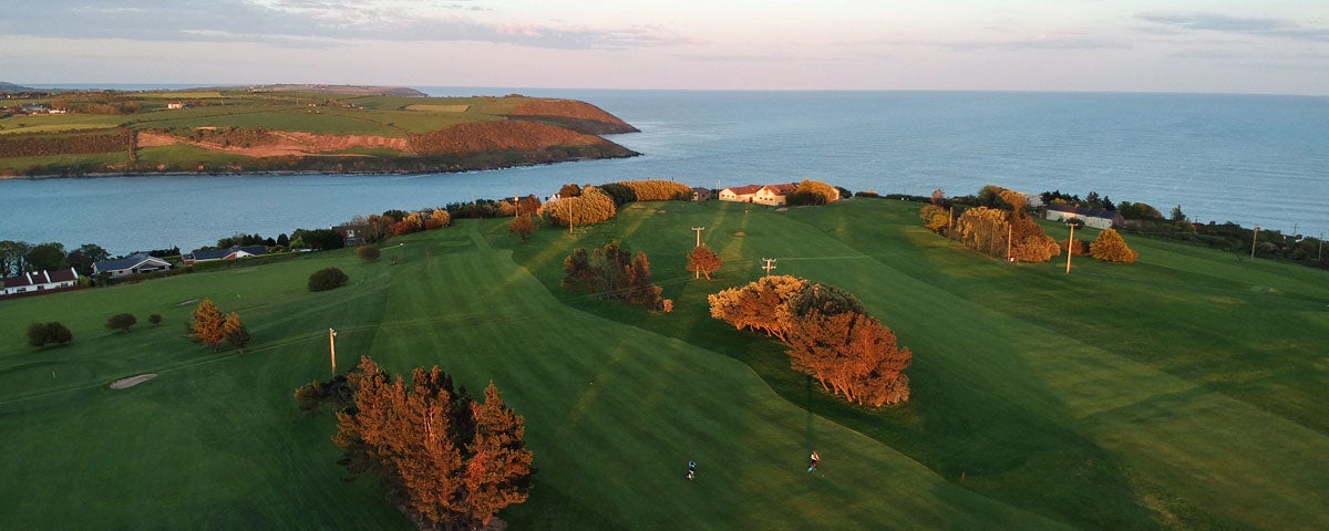 An aerial view of one the fairways at Youghal Golf Club with Youghal Bay in background set against an evening sky