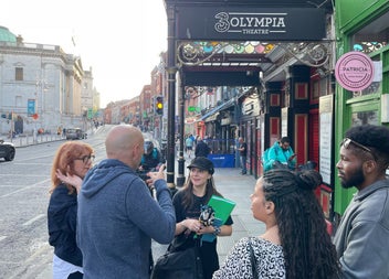 A walking group outside the Olympia Theatre as a guide shares stories with them
