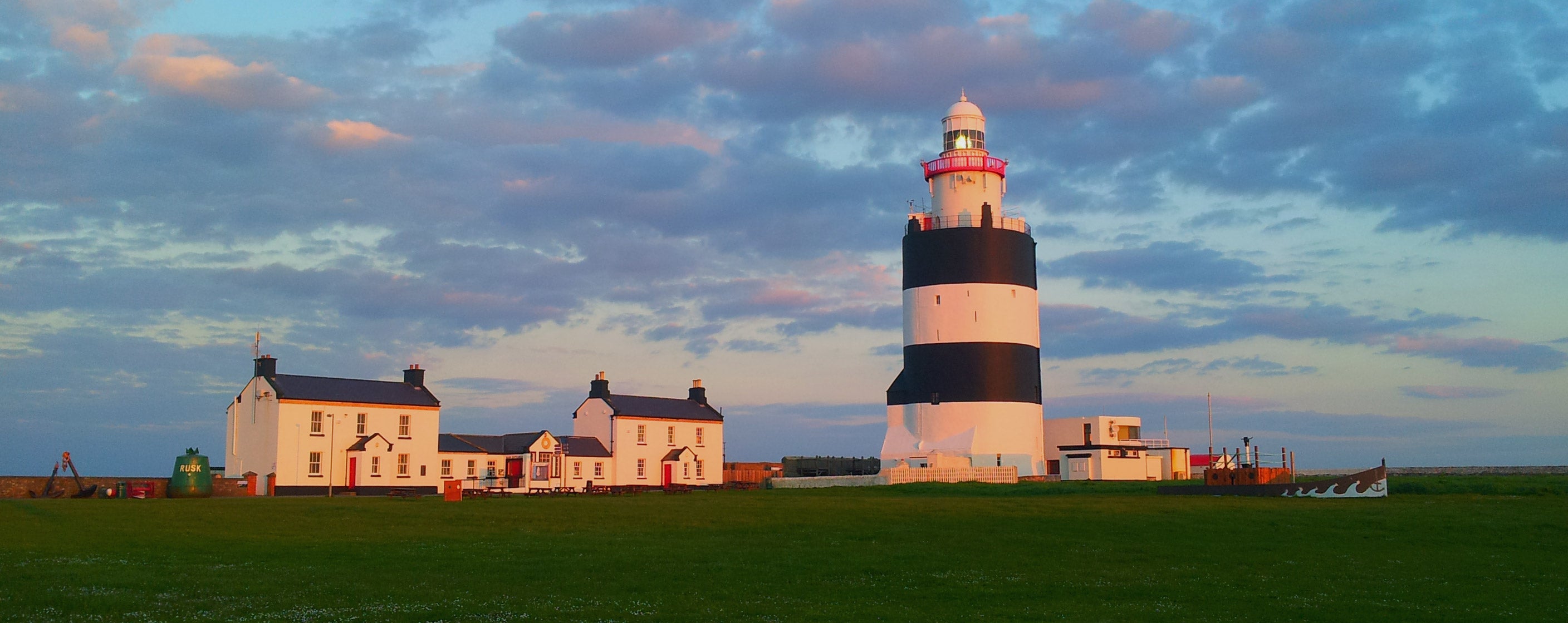 Blue skies over towering  Hook Lighthouse with cottages in the background