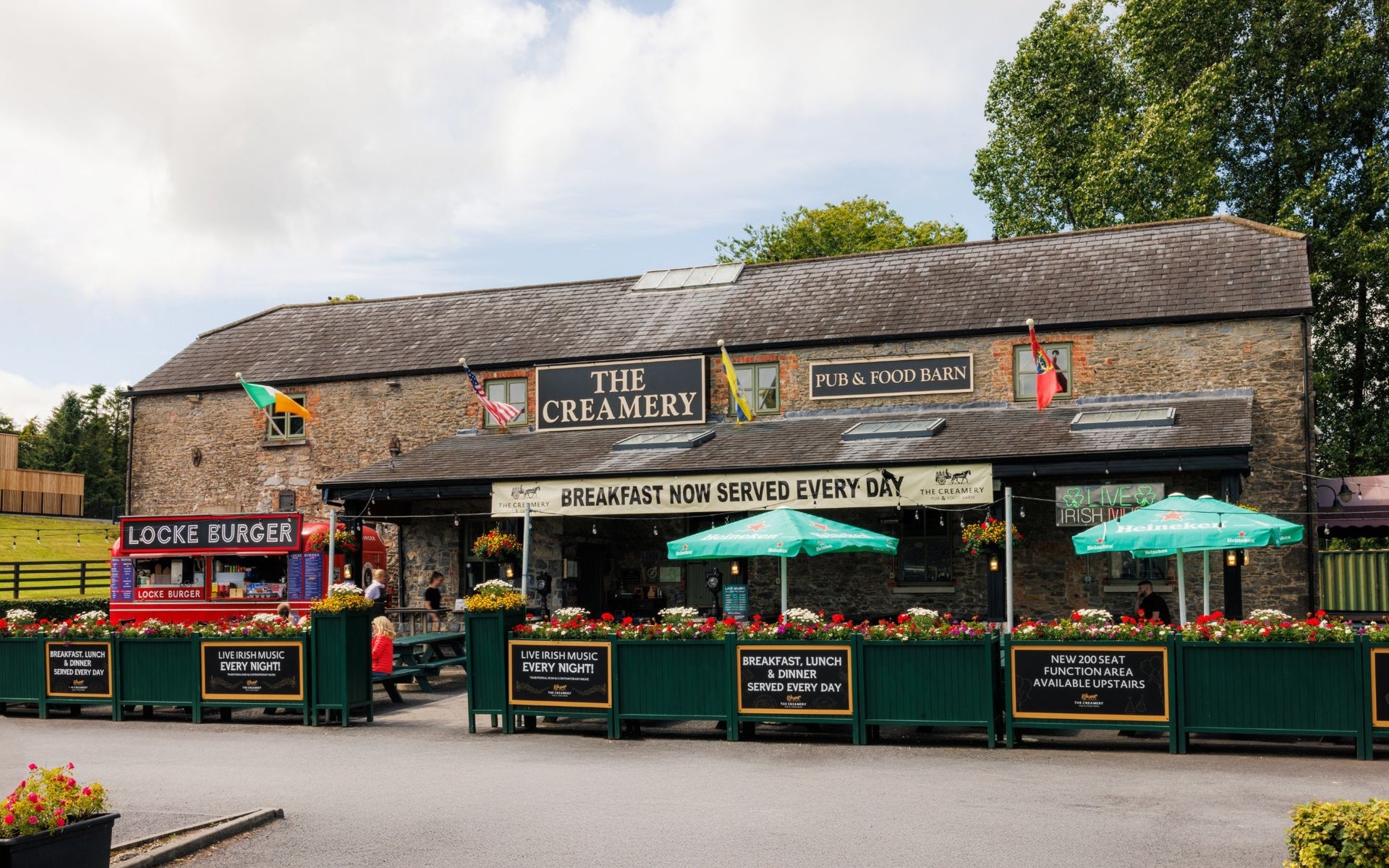 Exterior of an old stone building with outside dining area with green branded parasols
