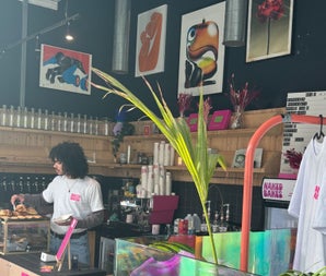 Coffee shop with paintings on the wall and a person serving pastries