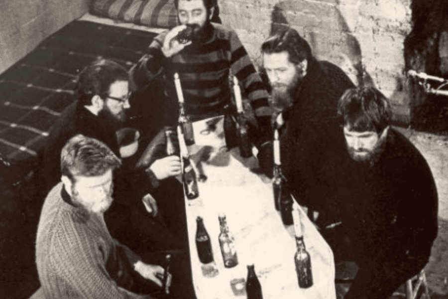Old black and white photo of group of men seated at pub table