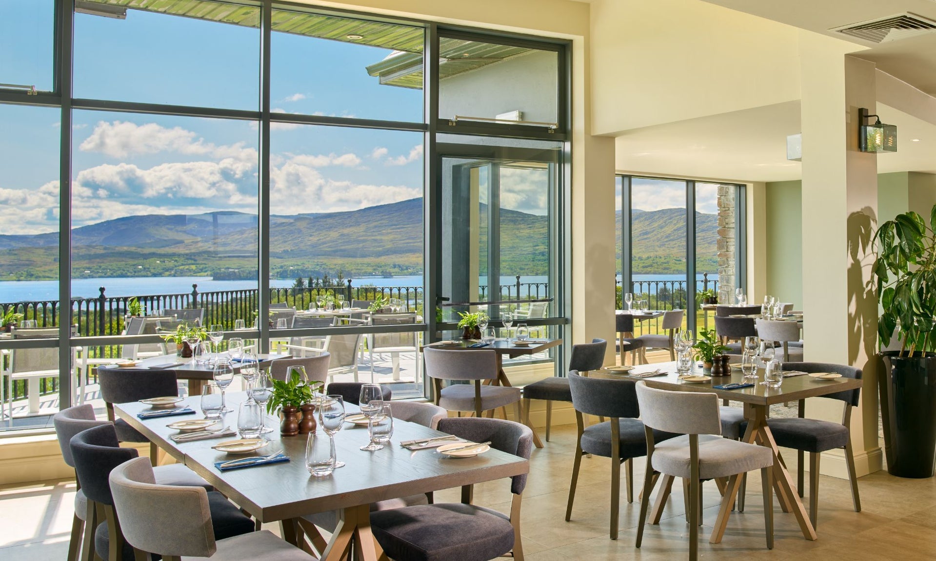 Interior of a brightly coloured restaurant with set tables and large panoramic windows with a view