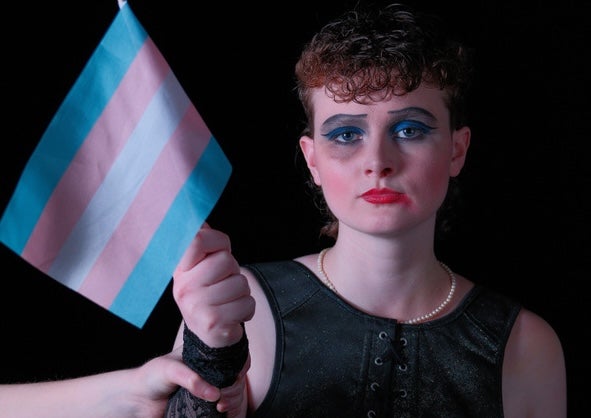 Roadkill Dublin Municipal Theatre at Smock Alley, a sad looking person wearing thick make-up, holding a small, stripy flag.