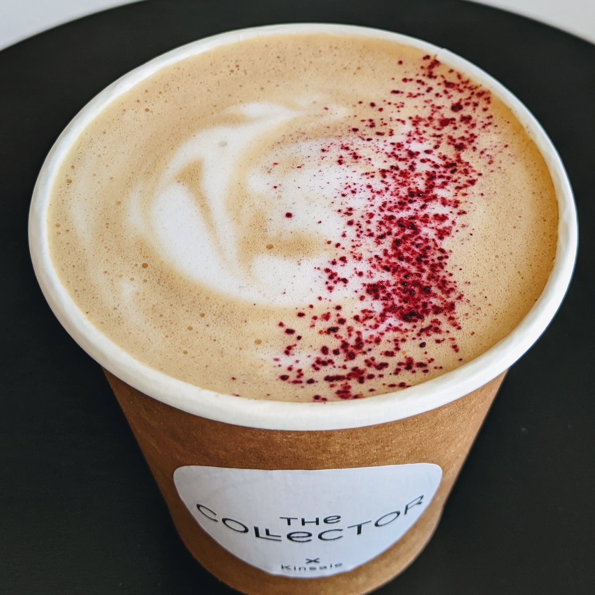 Filled take away coffee cup with pink sprinkles on the foam