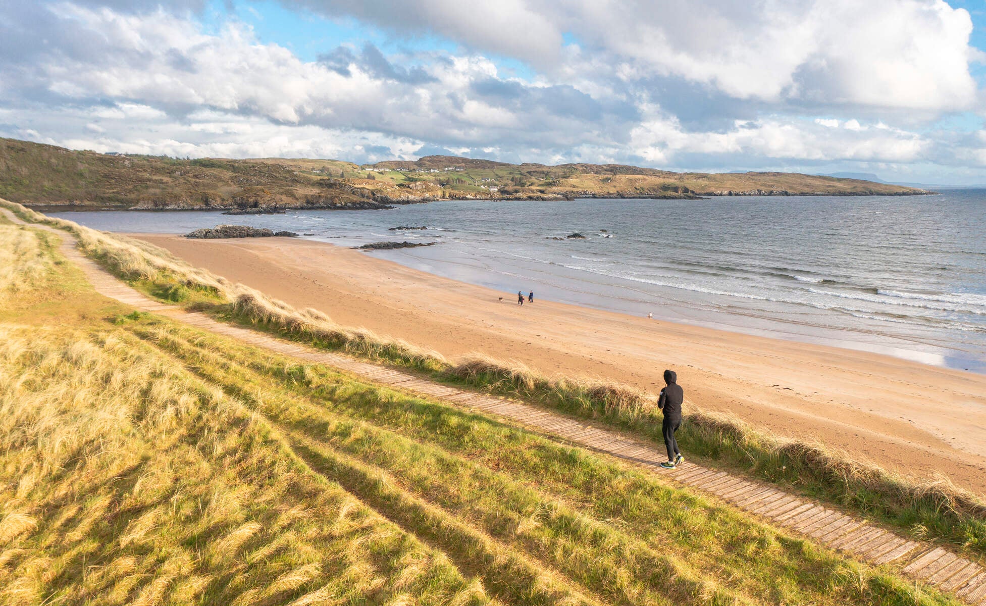 Person walking the boardwalk pathway onto Fintra Beach