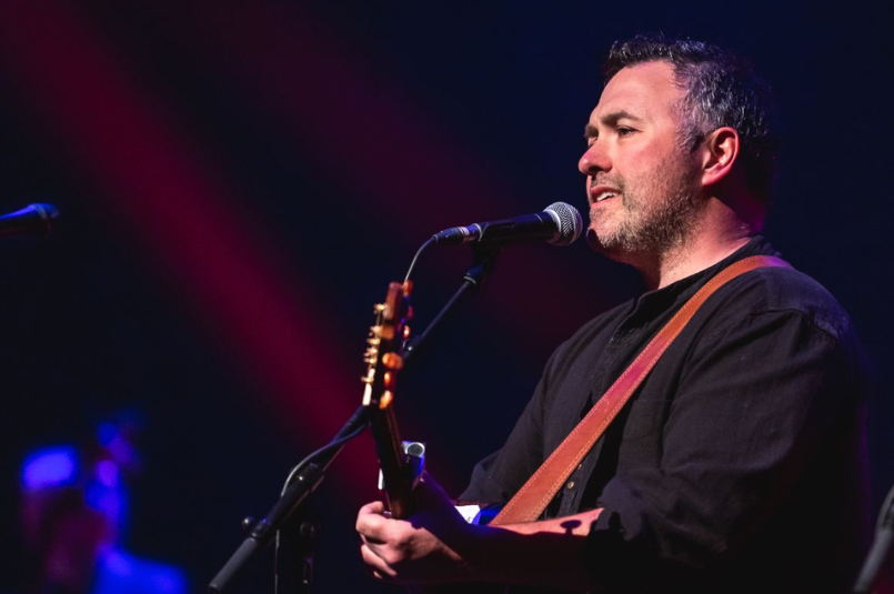 Ger O'Donnell - Guest Singer - a man in dark top playing a guitar and singing into a mic on stand.