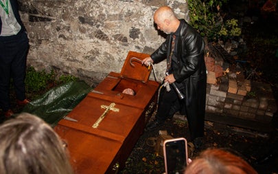 A tour guide showing people a coffin with a person in it