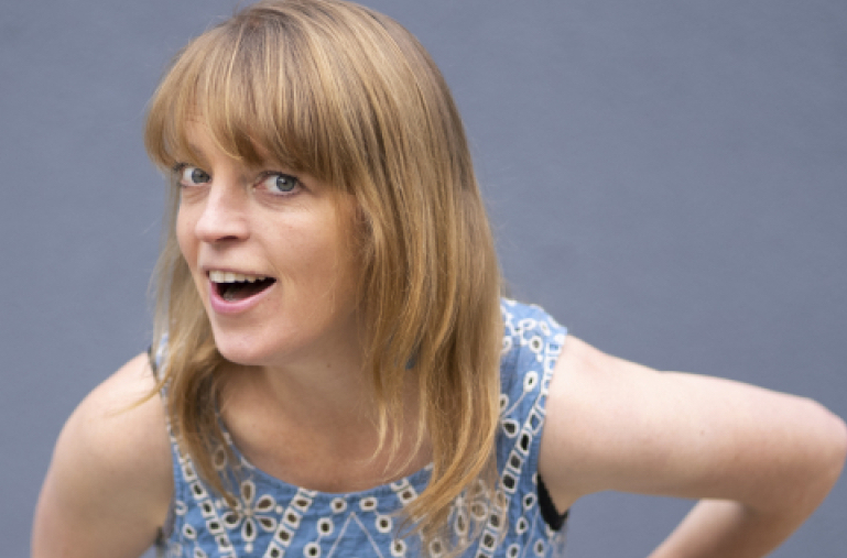 A woman in blue and white top is bending slightly forward, with mouth open appearing to be laughing.