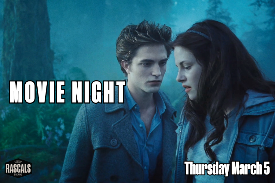 A man and woman standing near each other looking dramatic in a forest at twilight.