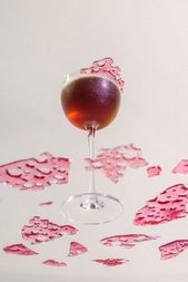 Looking up at a dark coloured cocktail from beneath a glass surface