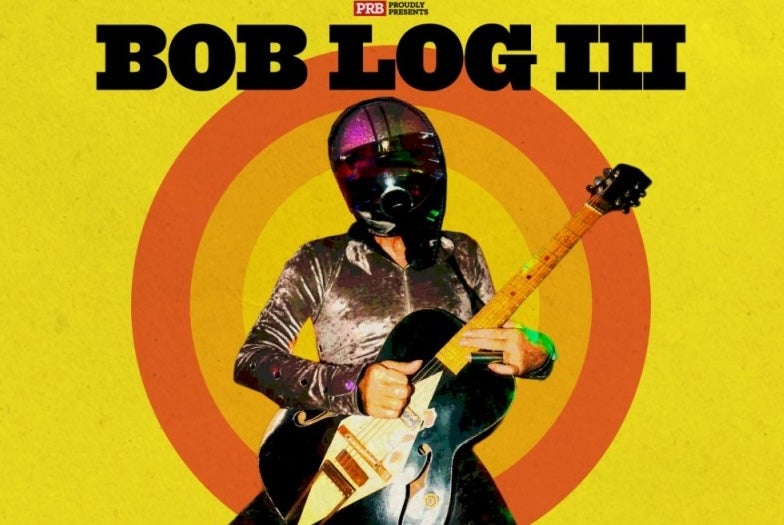 Bog Lob III poster in yellow with a man playing an electric guitar wearing a silver shirt and motorcycle helmet with black visor.