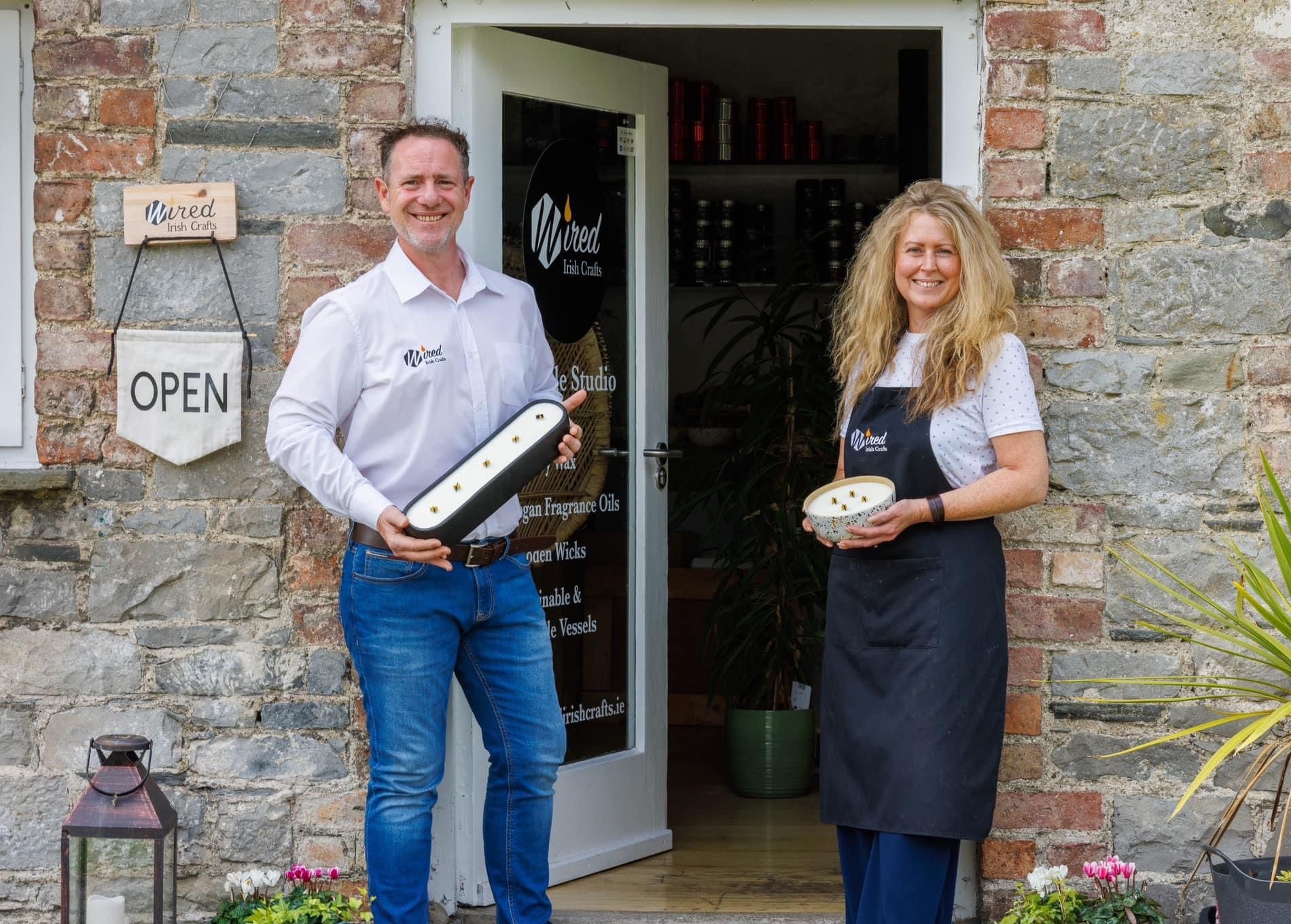 A lady and gentleman standing outside Wired Irish Craft holding candles